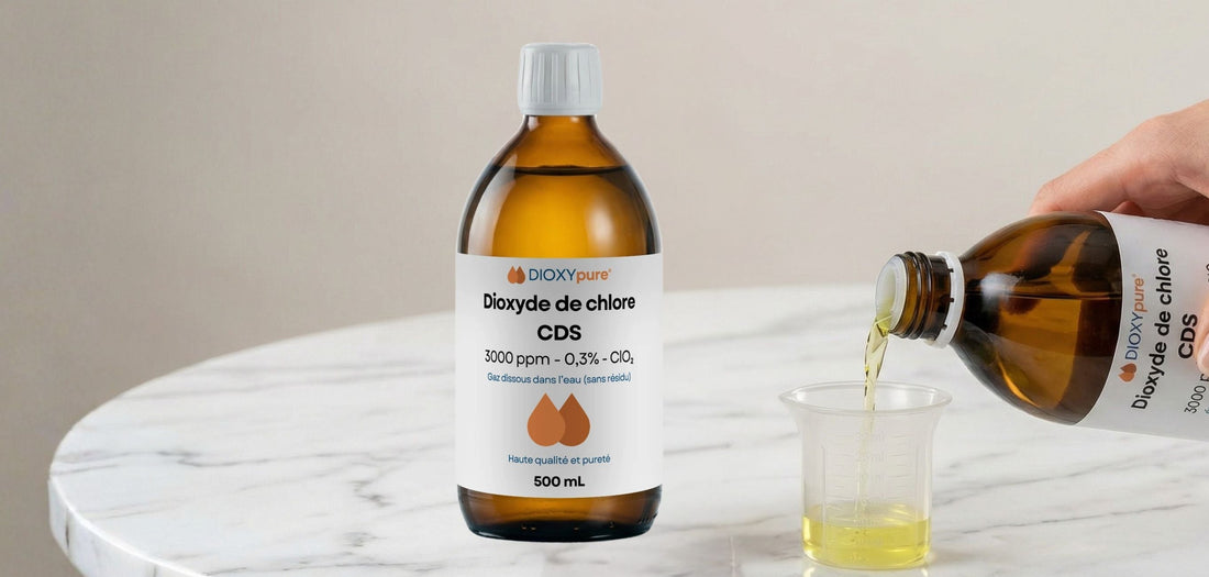 Bouteille de dioxyde de chlore CDS 500 mL, liquide jaune versé dans un gobelet sur table en marbre.